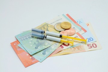 Syringes and bank notes on white background