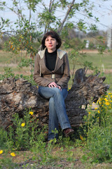 beautiful young woman sits on a tree in the park .