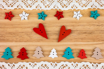 Two red hearts, snowflakes and trees on wooden background with lace. Button bears love. Button love. Wooden buttons. Post card for the Valentine.