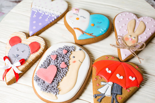 a collection of gingerbread cookies in the shape of a heart, muffins and animals on a white wooden background