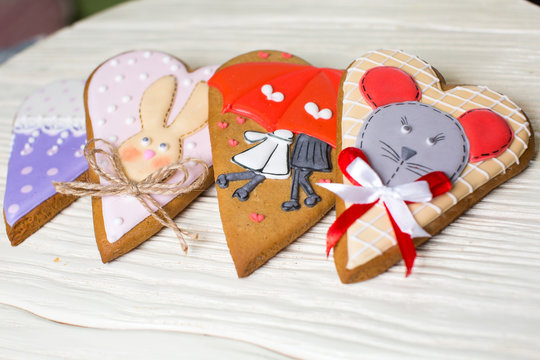 a collection of gingerbread cookies in the shape of a heart, muffins and animals on a white wooden background