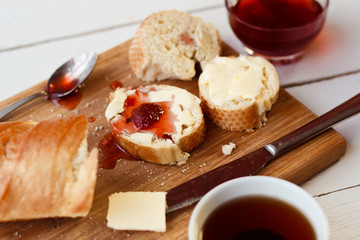Toasts with jam on plate and cup of tea on bright background