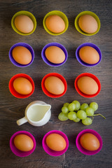 Eggs in colourful cupcake cups with grapes and a milk jar