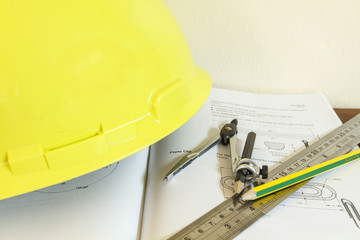 hard hat with pencil compasses and rulers/book on table and wall