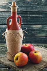 Bottle of wine and apples on background of jute