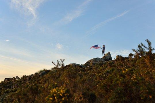 Man holding American Flag on top of hill
