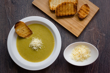 a plate of cream soup with grated cheese and grilled toasts