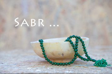 Пустая деревянная чаша и четки. Надпись sabr - означает...