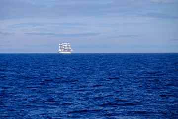 Segelschiff, Dreimaster, leuchtend weiß, auf weiter blauer, klarer Wasserfläche