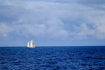 Segelschiff, Zweimaster, leuchtend weiß, auf weiter blauer, klarer Wasserfläche