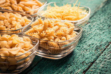 Various mix of pasta on wooden rustic background. Diet and food