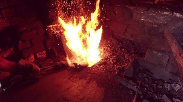 Worker adjusts the position of the preform in the fire furnace in the smithy