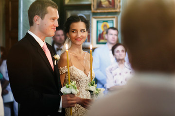 Happy emotional beautiful bride and cheerful groom with candles