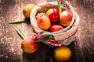 Fresh peaches in a basket on rustic wooden table.
