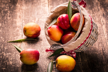 Fresh peaches in a basket on rustic wooden table.