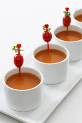 Tomato soup in bowls with a grape tomato and parsley stuck on a