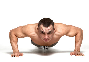 Muscle man making push ups in studio over  white background