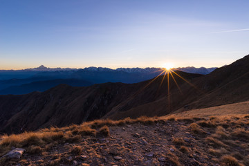 Mountain range at sunset, backlight with sunburst, italian Alps