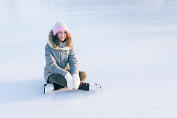 Fototapeta na wymiar Ice skating woman sitting on the ice smiling