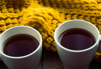 Two white cups of tea and scarf on old wooden desk