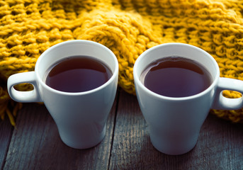Two white cups of tea and scarf on old wooden desk © tihayanadya