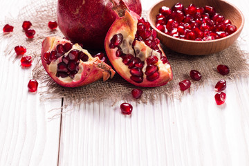 Some red juicy pomegranate, whole and broken, on rustic wooden table