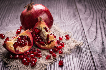 Some red juicy pomegranate, whole and broken, on rustic wooden table