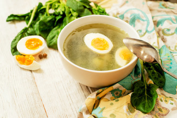 
healthy lunch , green soup with sorrel or spinach , boiled egg and spices on wooden background