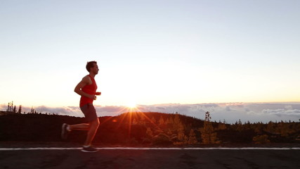 Running man - male runner training outdoors exercising on mountain road at sunset in amazing landscape nature. Fit handsome athlete jogger working out for marathon run outside in summer. - Powered by Adobe