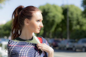 Female close-up portrait on the street. The girl carefully looks away.