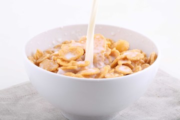 Milk flows in a bowl with corn and rice flakes