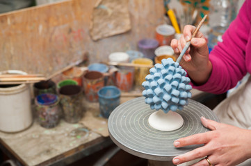 A pottery decorator painting a typical ceramic pine cone in his work table in Caltagirone, Sicily