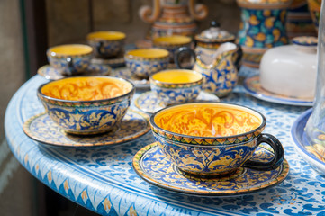 Close up view of a decorated ceramic teacup for sale in the table of a pottery workshop in...
