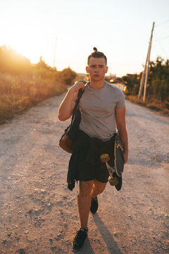 Image of a man with longboard going on road