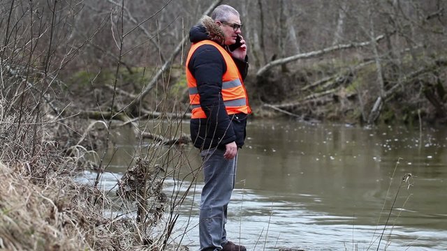 Environmental inspector with smartphone near the river
