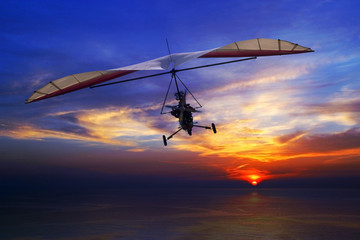 Fototapeta na wymiar The motorized hang glider in the sunset above sea