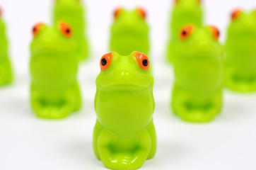 Platoon green toy frogs. Close up view. Frogs are dense structure. Identical and uniform.