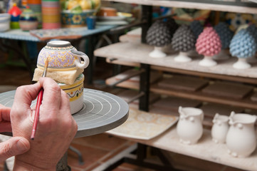 A pottery decorator finishing a ceramic small cup with floral motifs in his work table in Caltagirone, Sicily