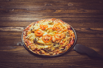 Italian pizza with pepperoni, tomatoes on wooden table. Top view with copy space
