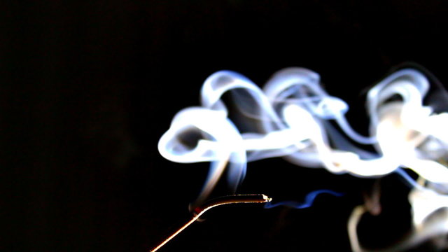 Smoke Rises from Incense. The incense stick smolders, smokes and breaks
