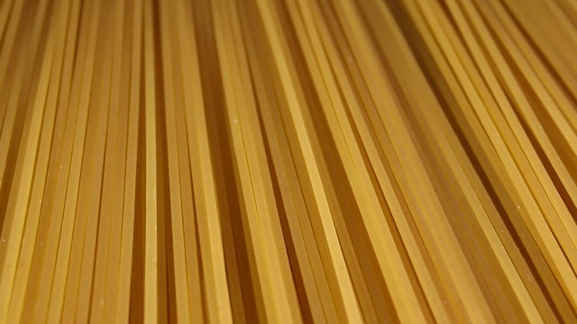 Part of dry yellow uncooked spaghetti. Macro shot.