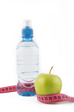 Green apple, bottle of water, measuring tape on a white background