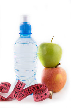Green and red apple, bottle of water, measuring tape on a white background