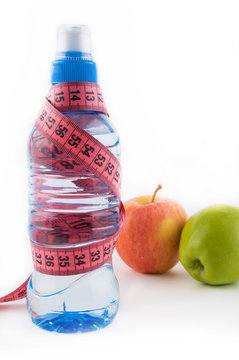 Green and red apple, bottle of water, measuring tape on a white background