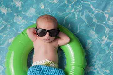 Newborn Baby Boy Floating on an Inflatable Swim Ring - obrazy, fototapety, plakaty