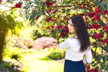 Young beautiful woman with long straight dark hair posing in spring garden