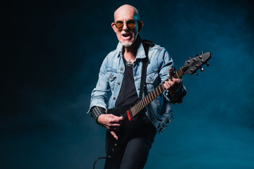 Bald heavy metal senior man with electric flying-v guitar in fro