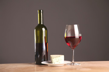 Refined still life of wine, cheese and grapes on wicker tray on wooden table