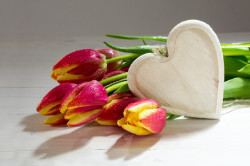 Fresh red orange tulips and a wooden heart, love decoration for