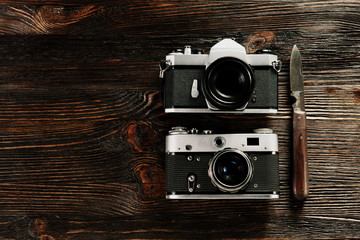 The old film cameras and the rusty german knife on the old wooden table.